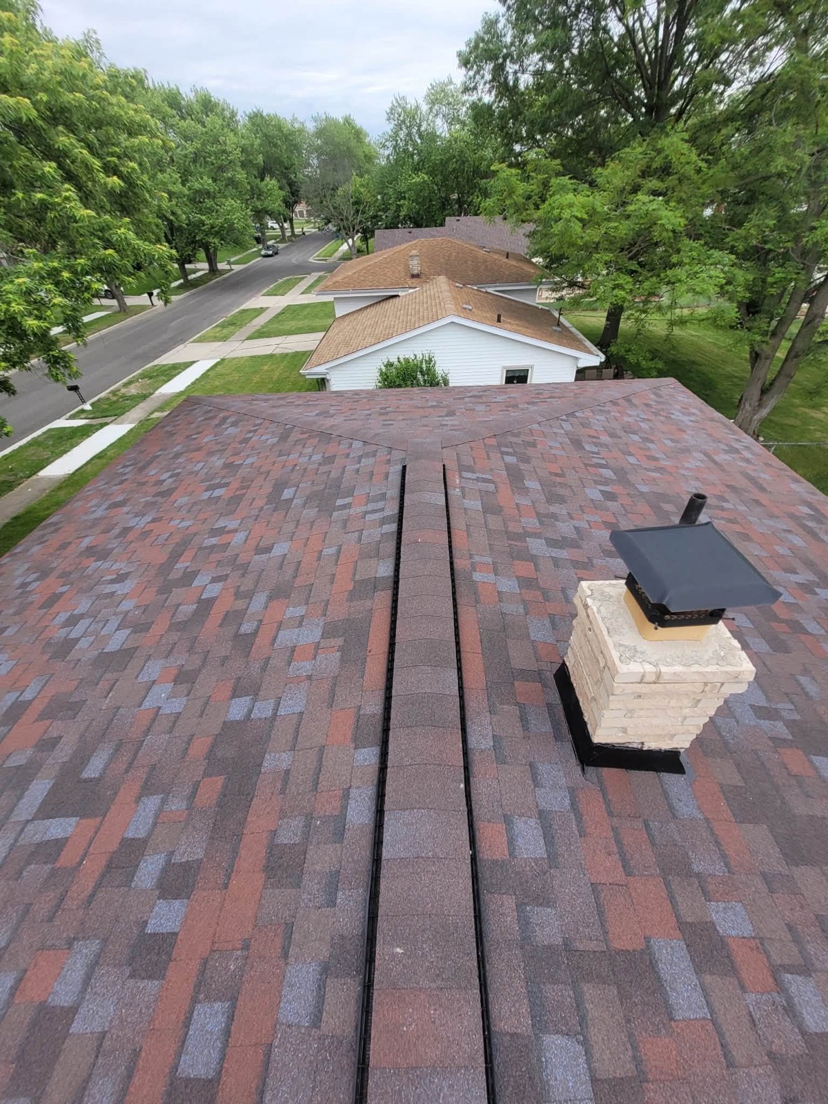 New shingle roof with ridge vent and stone chimney