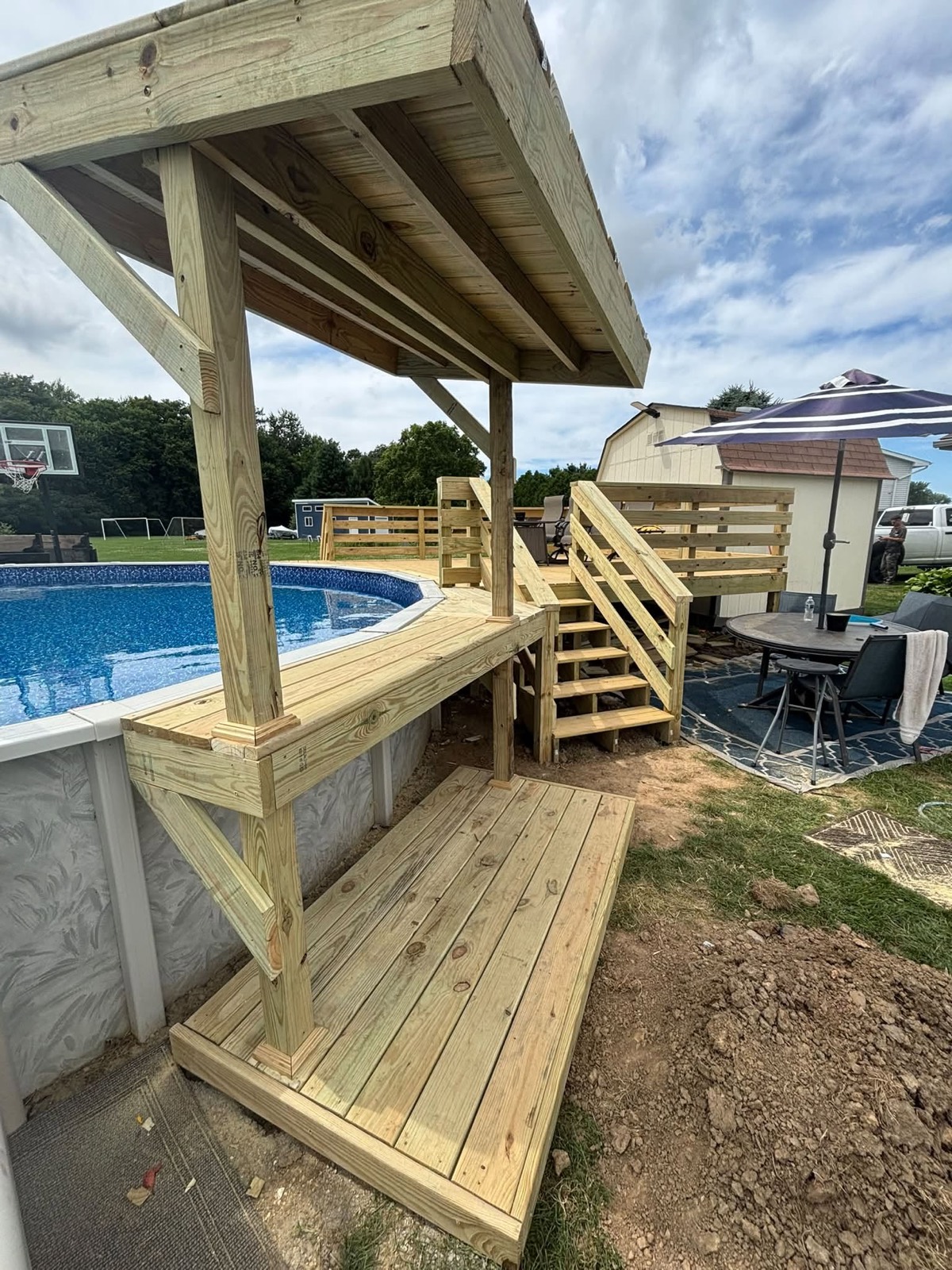 Custom pool deck with stairs, railing, and covered bar area