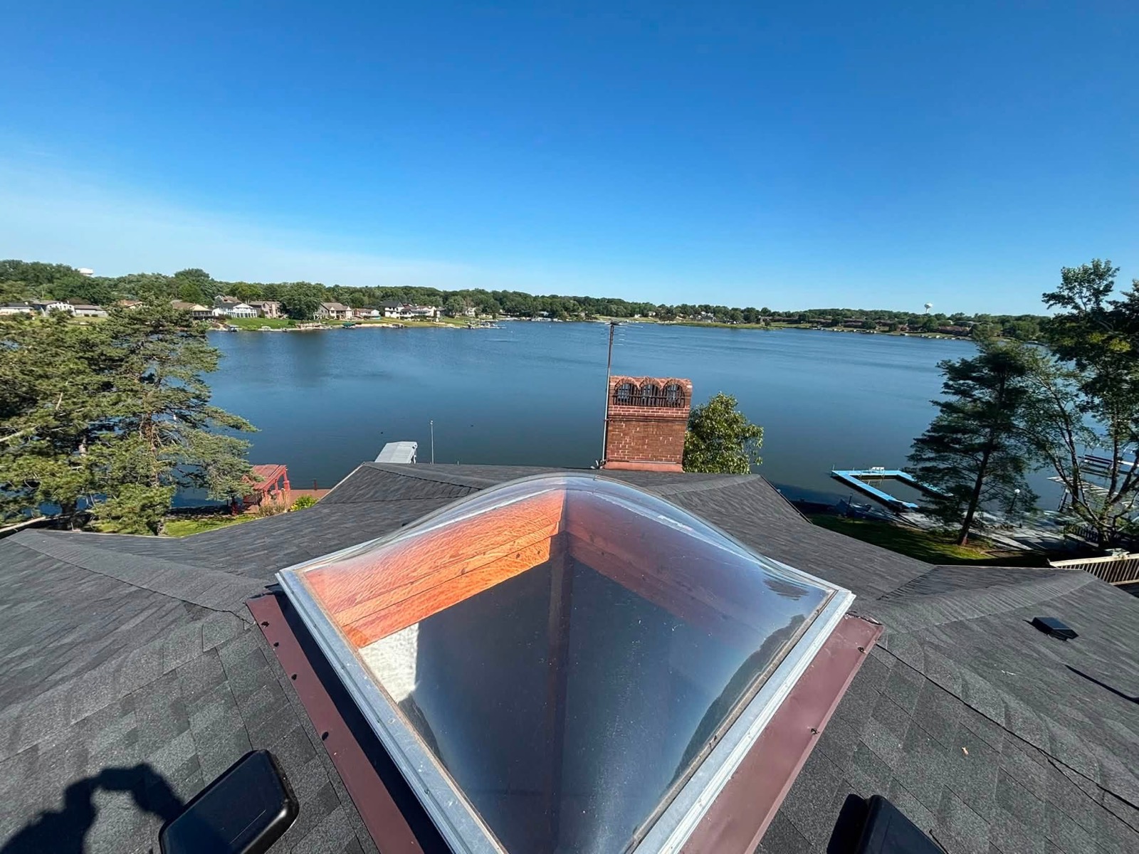 New skylight and brick chimney on a shingle roof overlooking a lake in Northwest Indiana